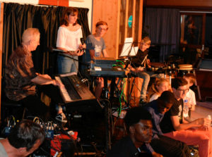 Jean-Luc au piano, Marianne debout, Arthur au clavier, Athis à la batterie. Au premier rang : Michael, Jamescy, Charlotte, Timothée et Sylvain